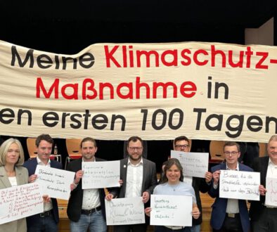 Die OB-Kandidaten stehen vor einem Banner "Meine Klimaschutzmasßnahme in den ersten 100 Tagen"